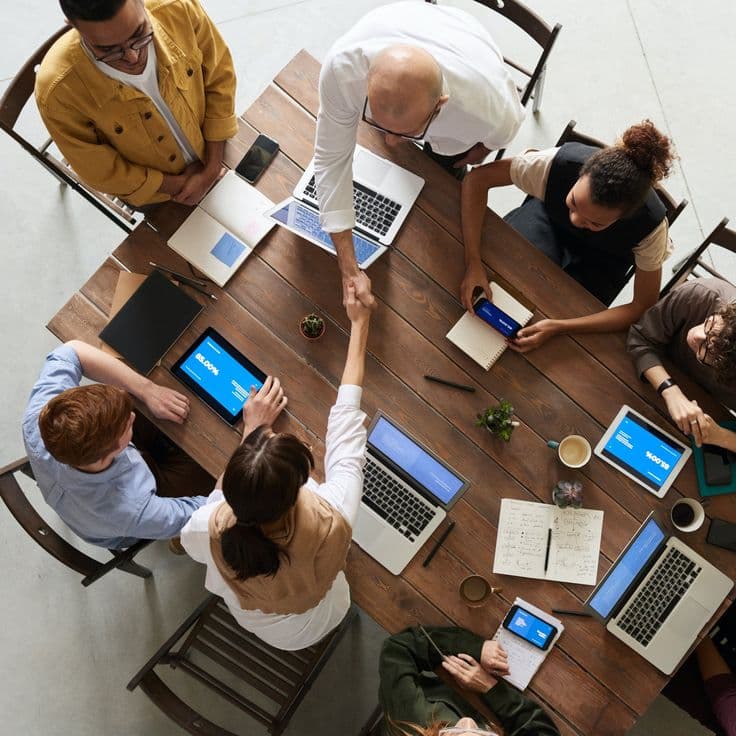 Overhead view of a team meeting around a table, sealing an agreement with a handshake